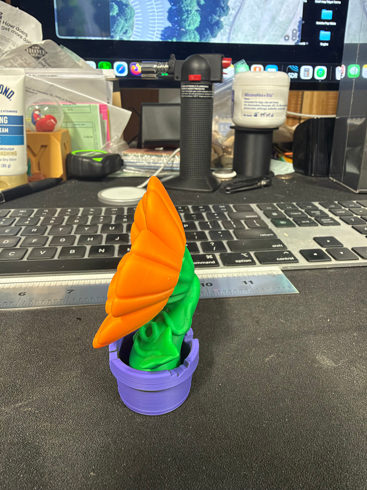 Orange flower figurine in purple pot, side view