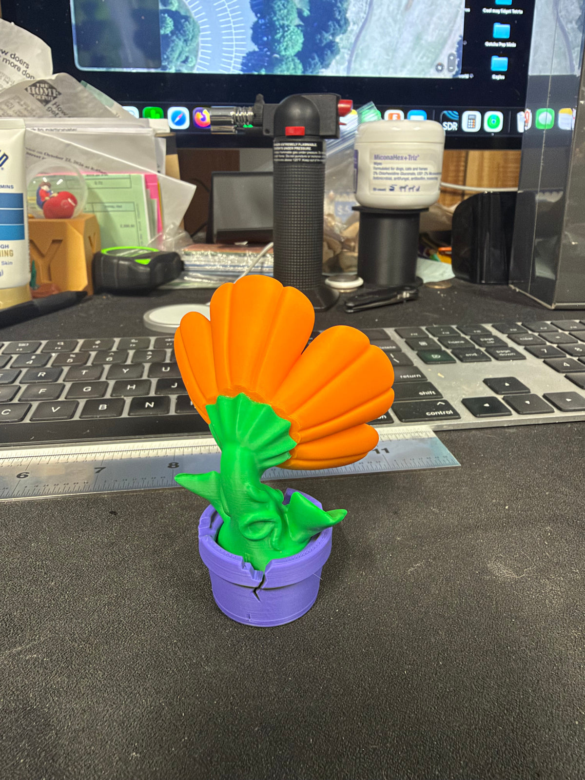 Flower figurine showing green stem and purple pot, rear view